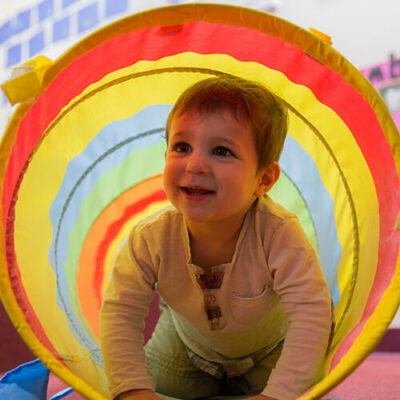 Older infant playing in play tunnel