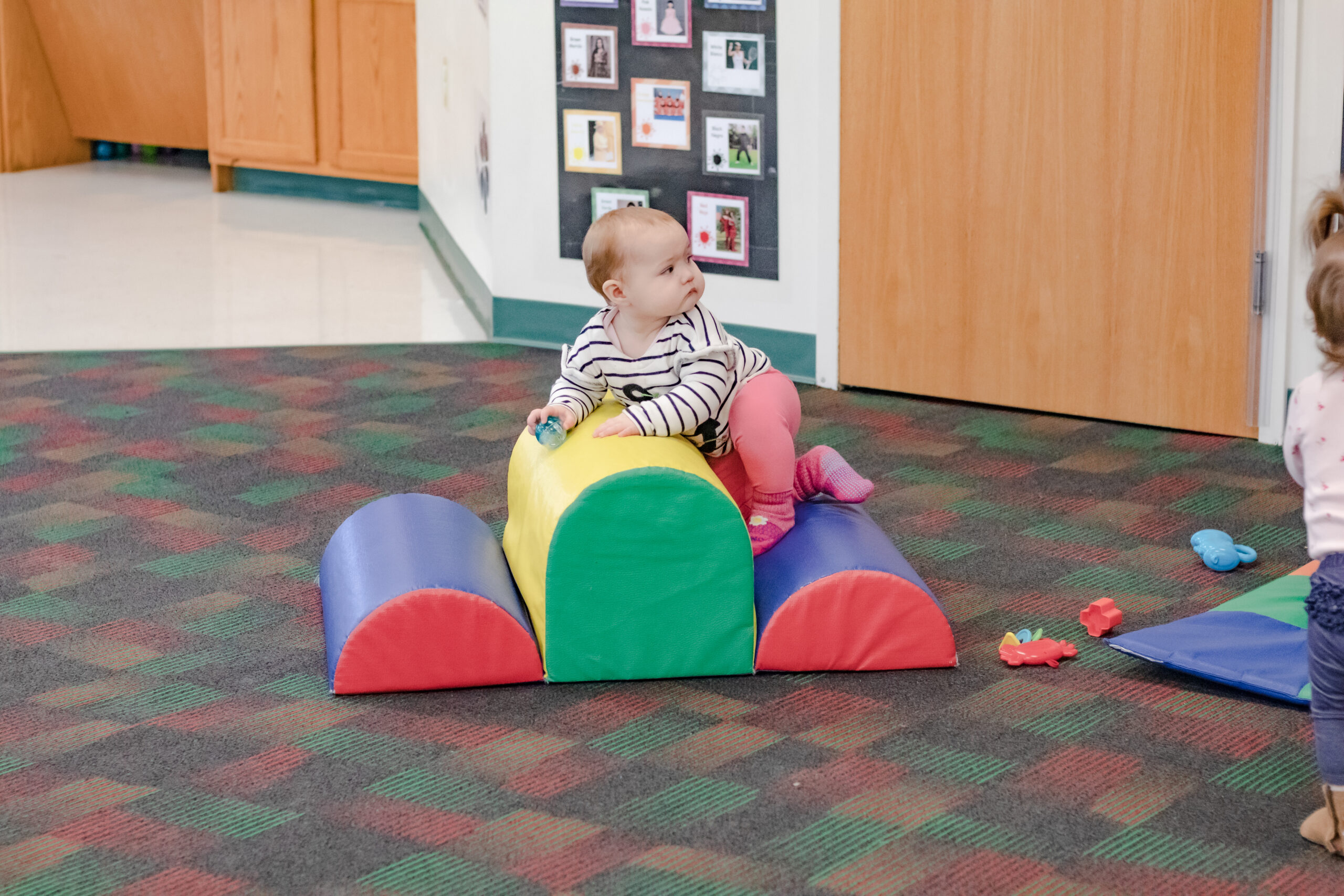 Infant climbing on soft arches in play area
