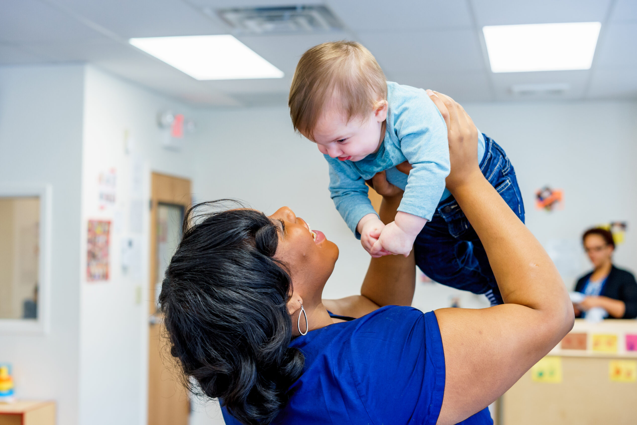 Teacher holding infant up in the air